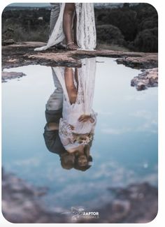 a bride and groom are reflected in the water