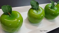 three green apples sitting on top of a white plate