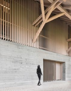 a person walking in front of a building with wooden slats on the ceiling and walls