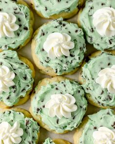 green frosted cookies with chocolate chips and white icing are arranged on a baking sheet