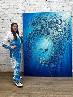 a woman standing in front of a large painting with fish swimming through the blue water