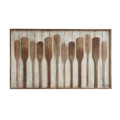 wooden spoons lined up in a row against a white wall with wood planks