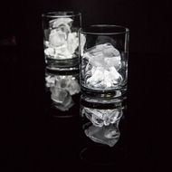 two glasses filled with ice sitting on top of a black table next to each other