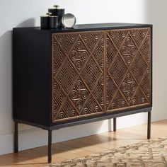 a black and brown cabinet sitting on top of a wooden floor next to a rug