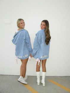 two women standing next to each other in front of a white wall wearing denim jackets