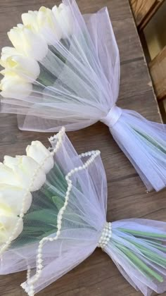 two white tulle bouquets sitting on top of a wooden table