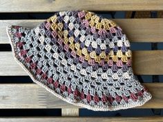 a crocheted hat sitting on top of a wooden bench