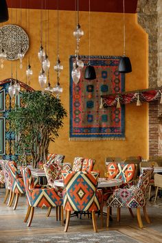 a dining room filled with lots of colorful chairs and tables next to a potted plant