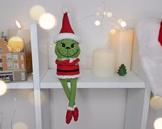 a knitted christmas ornament sitting on top of a shelf next to a candle