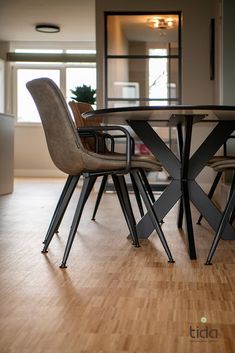 a dining room table and chairs with wood flooring in front of a large window