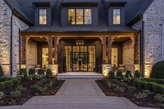 the front entrance to a large home with stone pillars and lights on it's sides