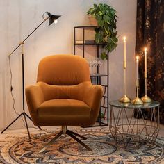 an orange chair sitting on top of a rug next to a table with two candles