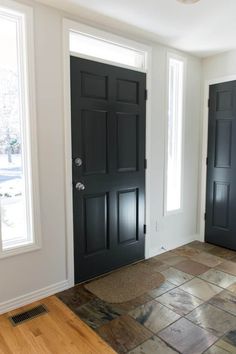 two black doors in a white room with wood flooring and tile on the floor