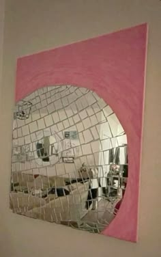 a mirror that is on the side of a wall in a room with pink and white walls