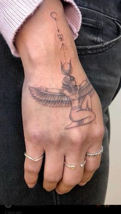 a woman's hand with a tattoo on it and a bird flying above her