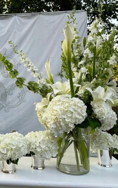 white flowers and greenery in vases on a table