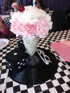 a vase filled with pink and white flowers sitting on top of a black and white checkered table