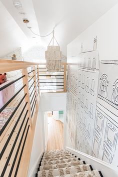 a staircase leading up to a room with drawings on the wall and carpeted floor