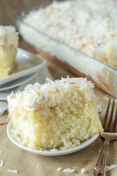 a piece of coconut cake on a plate with a fork next to the rest of the cake