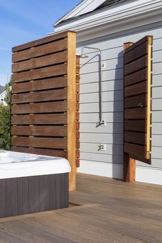 a hot tub sitting on top of a wooden deck next to a building with shutters