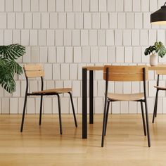 three chairs and a table in front of a white brick wall with a potted plant