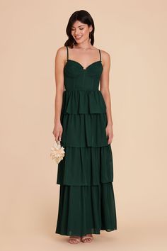 a woman wearing a green dress with spaghetti straps and tiered ruffles on the bottom