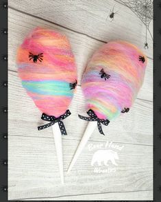 two candy lollipops decorated with spider webs and pink, blue, yellow and green yarn