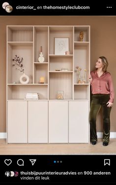 a woman standing in front of a bookcase with flowers and vases on it