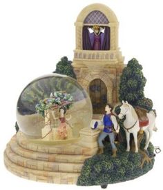 a snow globe sitting on top of a table next to a white horse and carriage