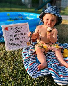 a small child sitting on a blanket with an ice cream cone in his hand and a sign that says it only took 11 months to get this summer