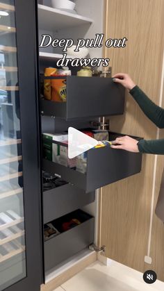 a woman is opening the drawers in a refrigerator