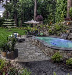 an outdoor hot tub surrounded by landscaping and trees