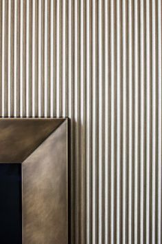 a square metal object sitting on top of a wooden table next to a striped wall