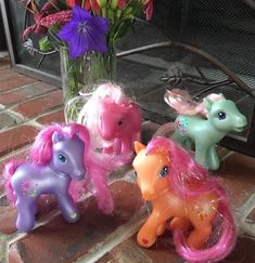 three little pony figurines sitting next to each other in front of a fireplace