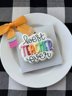 a decorated cookie on a plate that says best teacher ever