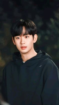 the young man is wearing a black hoodie and looking at the camera with an intense look on his face