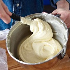 a person mixing batter in a metal bowl