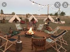 a fire pit surrounded by lawn chairs and tents with lights strung across the sky above