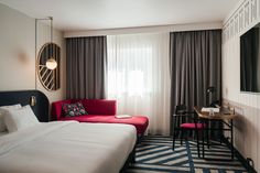 a bed room with a neatly made bed next to a desk and chair in front of a window