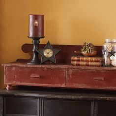 an old dresser with candles and books on it