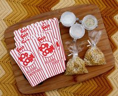 three bags of popcorn sitting on top of a wooden tray