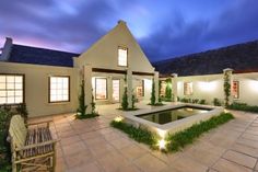 a large house with a pool in the middle of it at night, surrounded by greenery