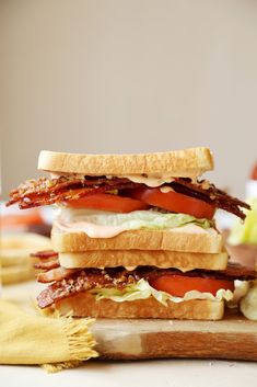 a bacon, lettuce and tomato sandwich on a cutting board