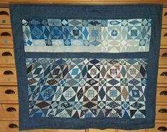 a blue and white quilt hanging on a dresser