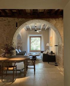 an arched doorway leads into a living room with stone walls and floor to the dining area