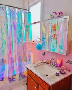 a bathroom with a sink, mirror and colorful shower curtain in it's corner