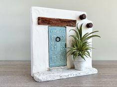 a white house with a blue door and potted plant next to it on a wooden table