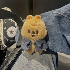 a teddy bear with a bow tie sitting in someone's jeans and holding onto their shoes