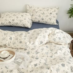 an unmade bed with blue and white sheets, pillows and a tea cup on it