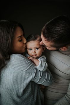 a man and woman holding a baby in their arms